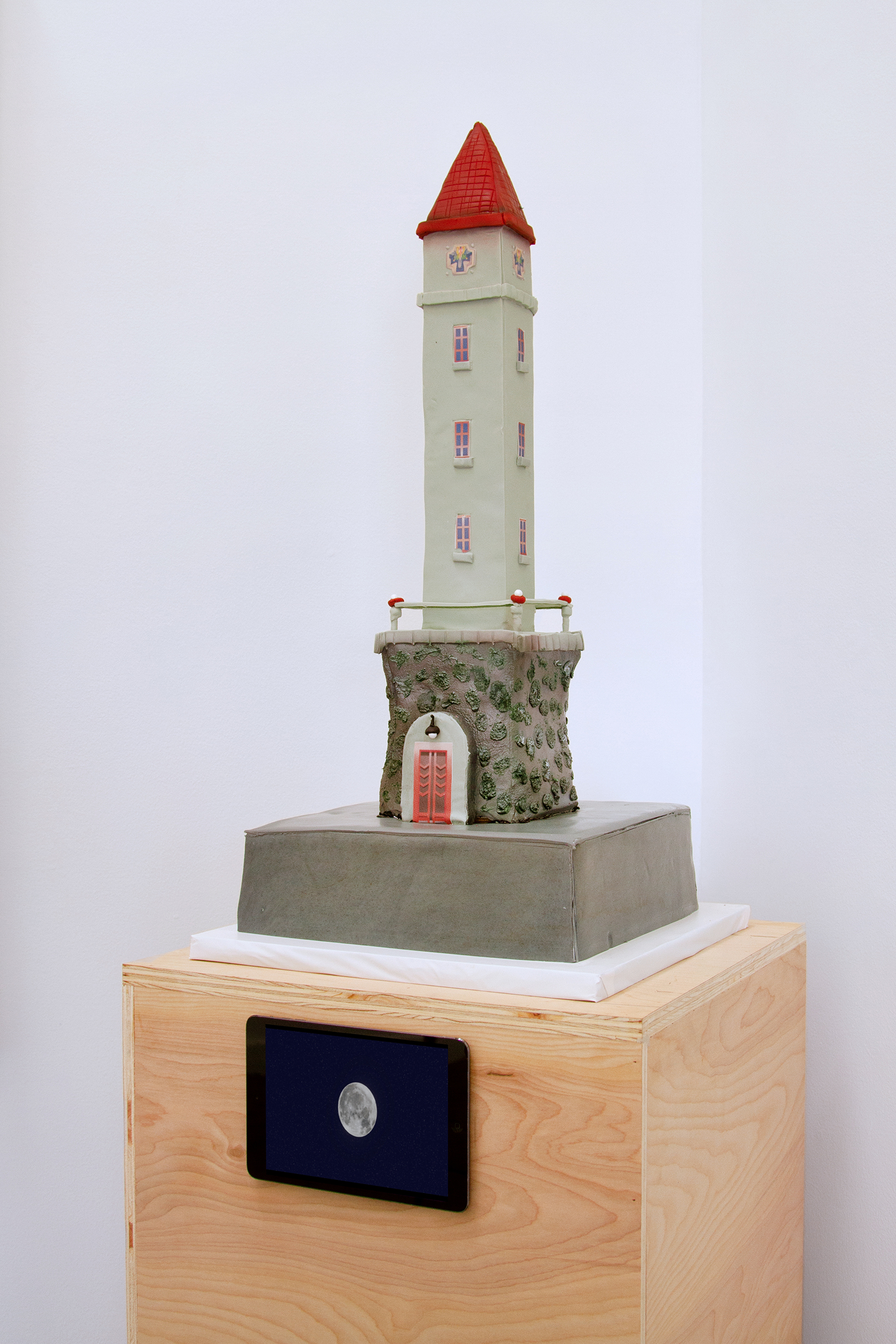 3/4 view of a tower shaped cake on a wooden pedestal